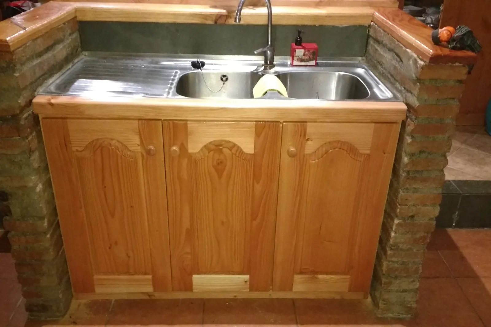 Mueble de lavaplatos de pino sobre muro de piedra